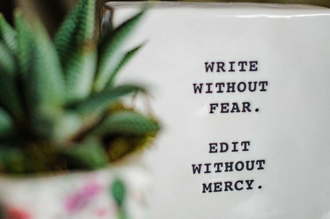 white tile that says write without fear, edit without mercy.