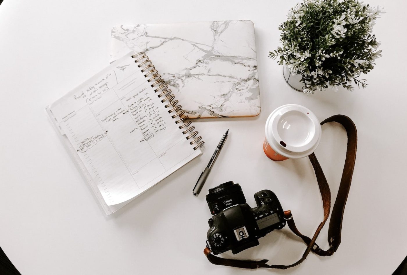 table with laptop, notebook, camera and coffee