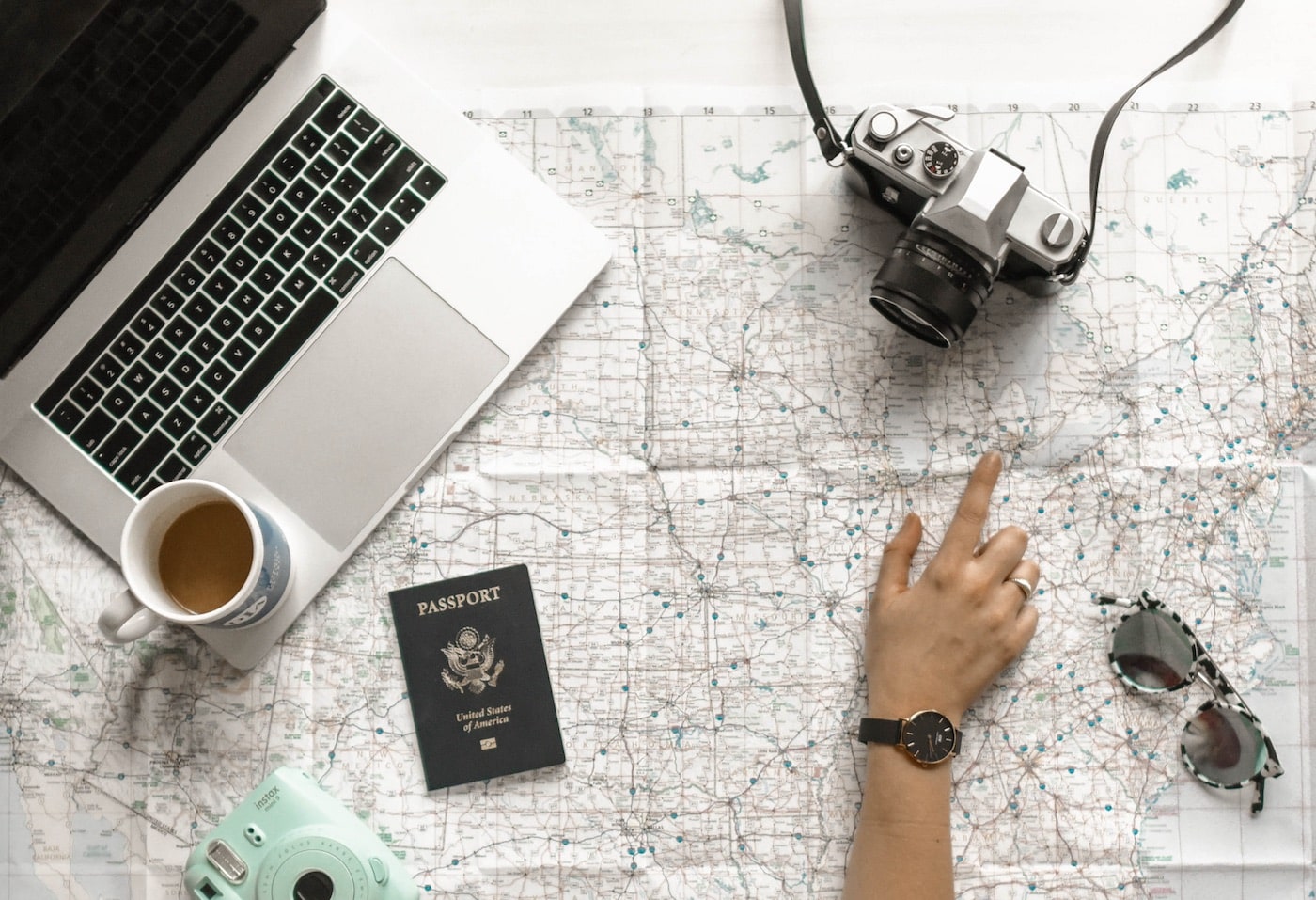 laptop on top of map with camera, passport and coffee