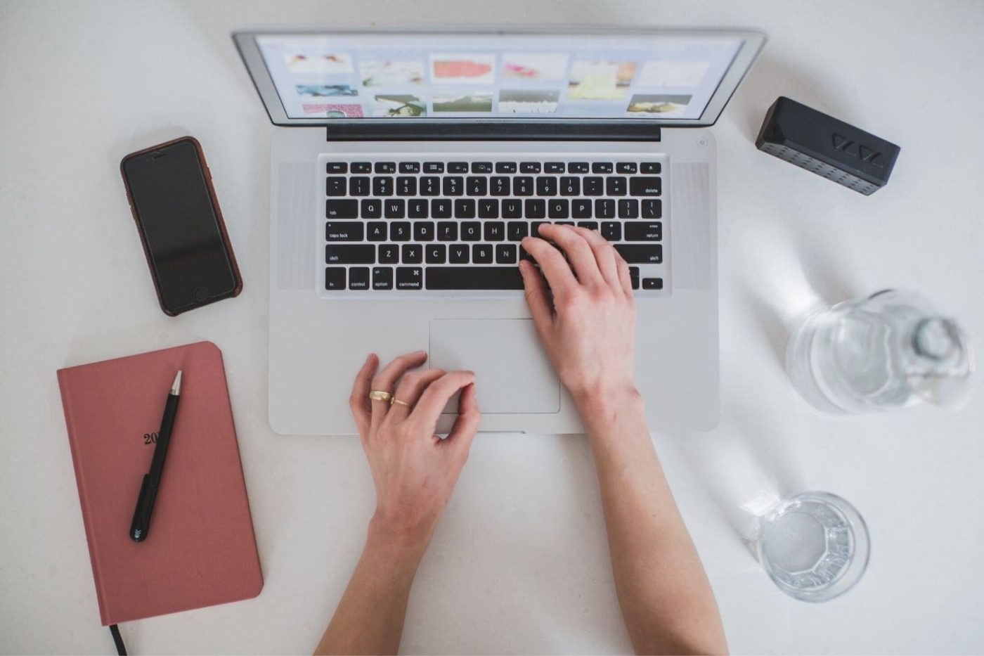 Person using a laptop with a notebook and phone next to them