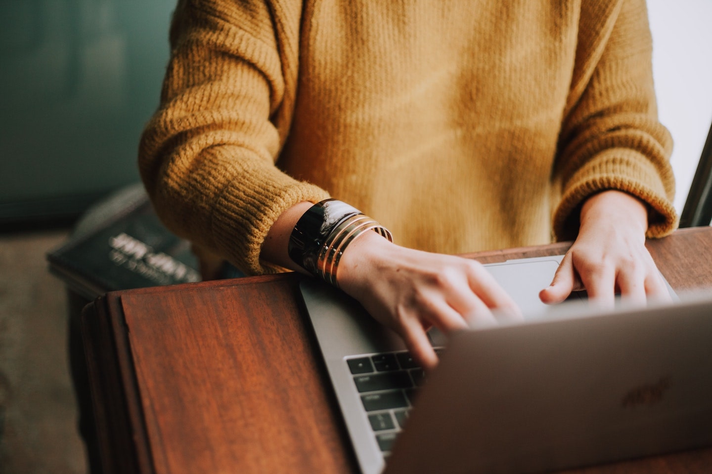 woman in yellow sweater typing on laptop