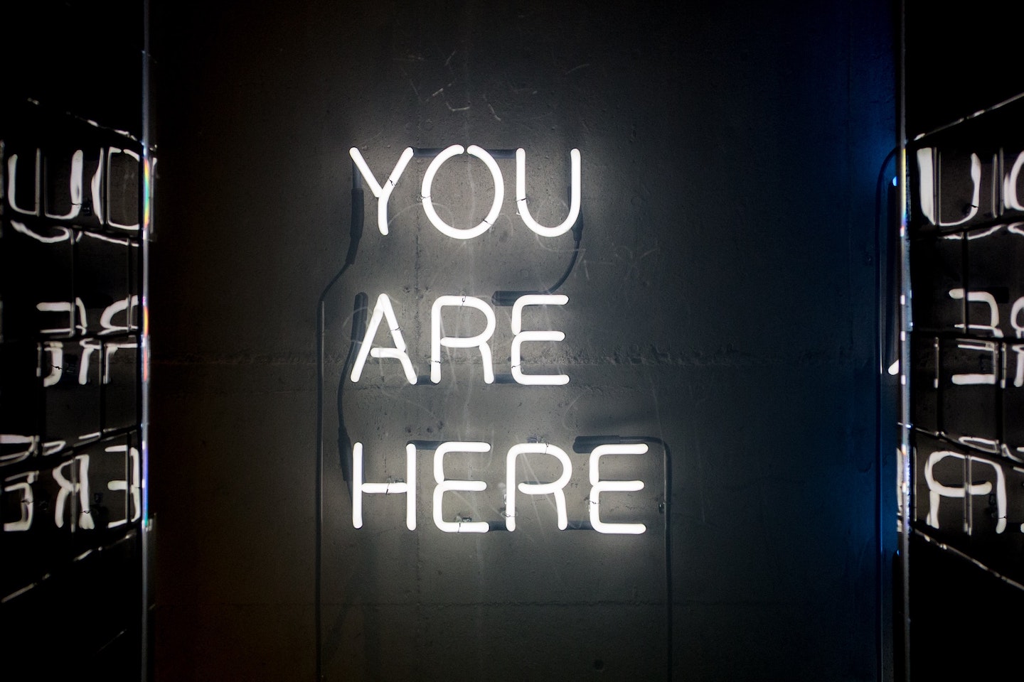 You Are Here written in white neon lights on a black background