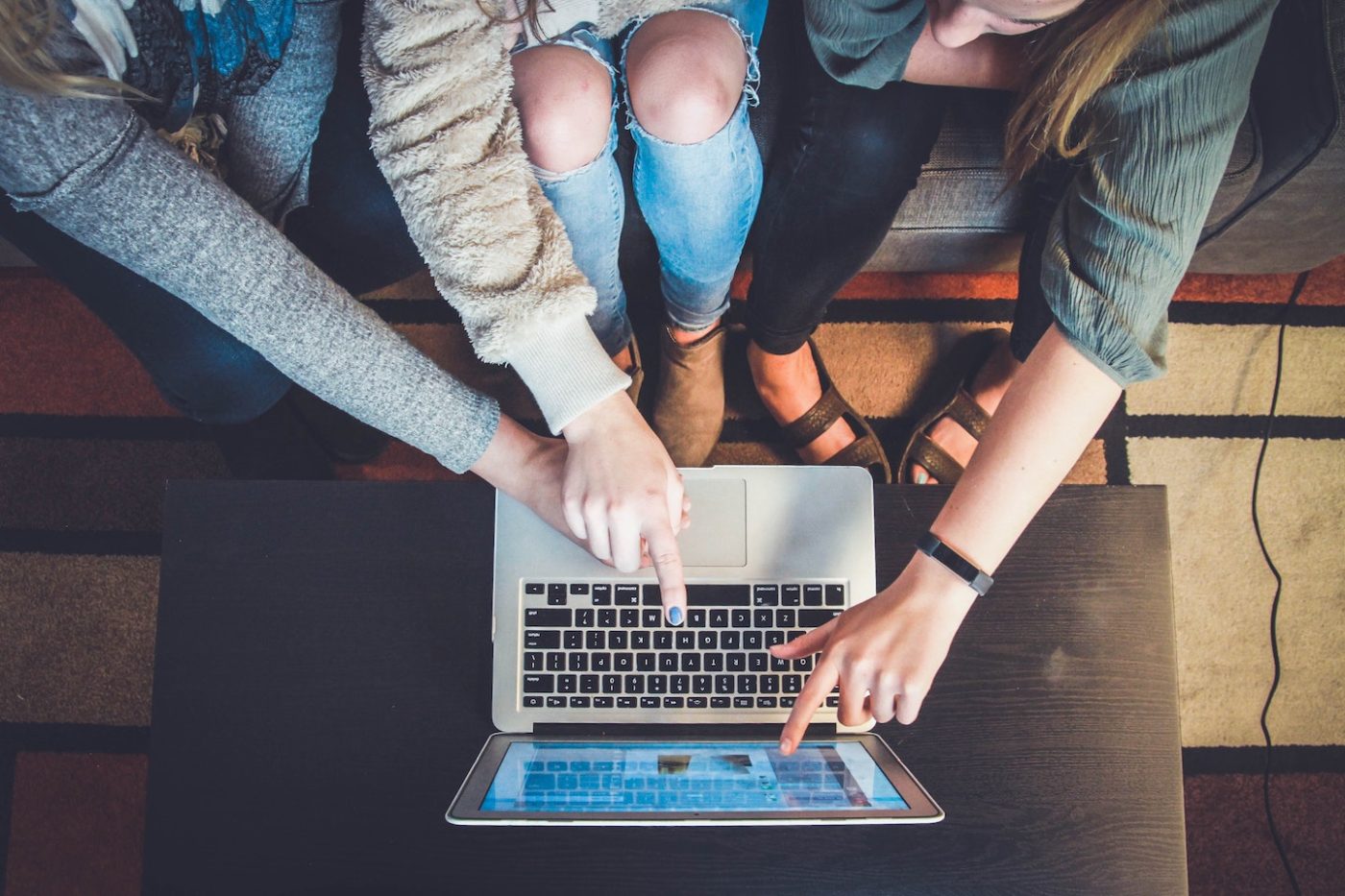 three girls pointing at computer screen