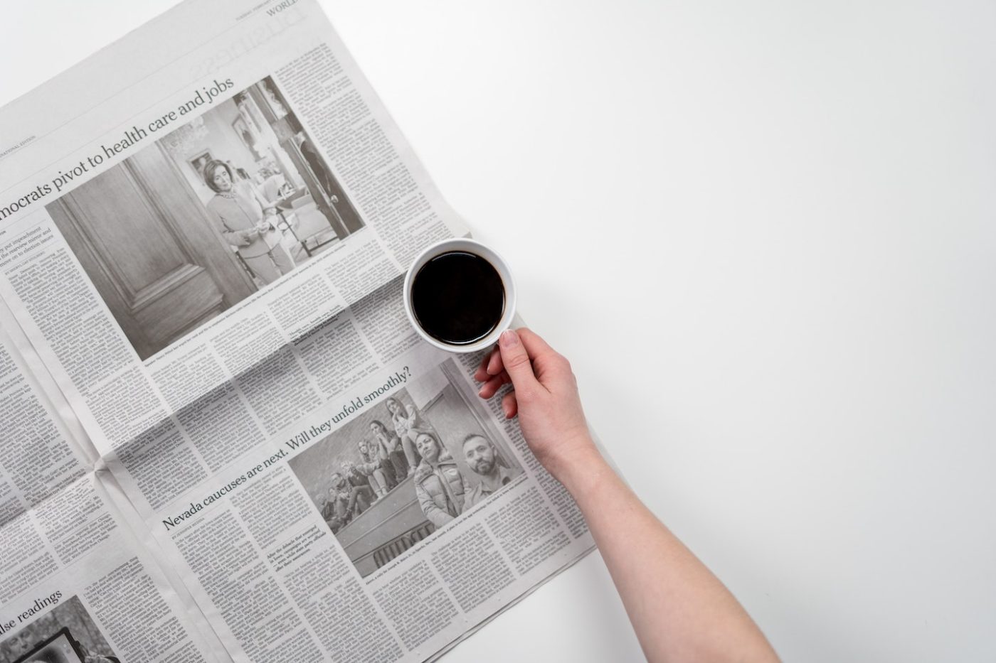 Persons arm onto of a newspaper holding a cup of coffee headline examples