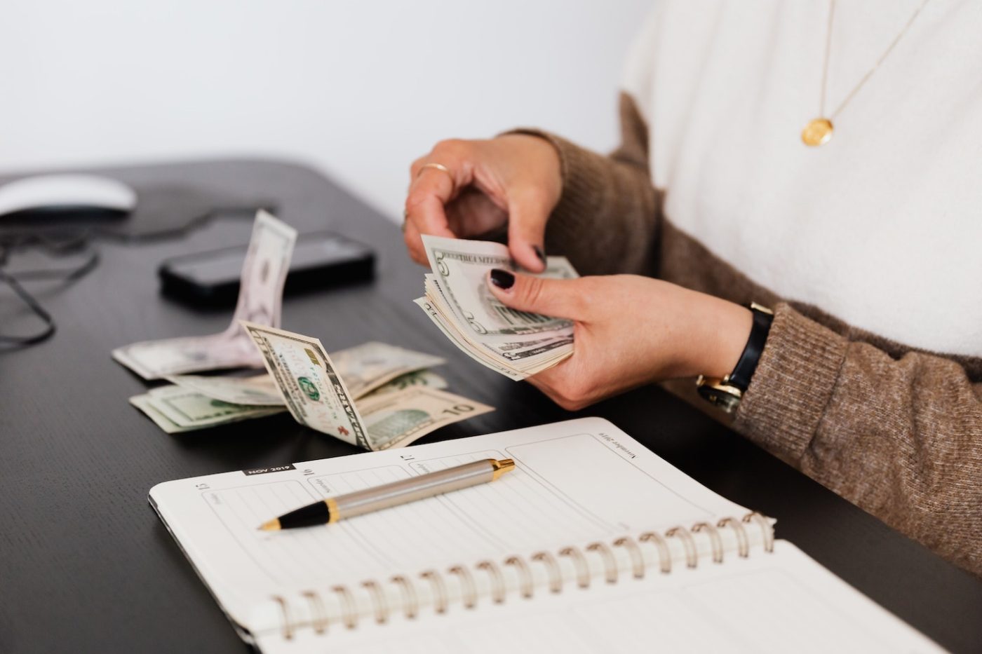 person counting money over a notebook